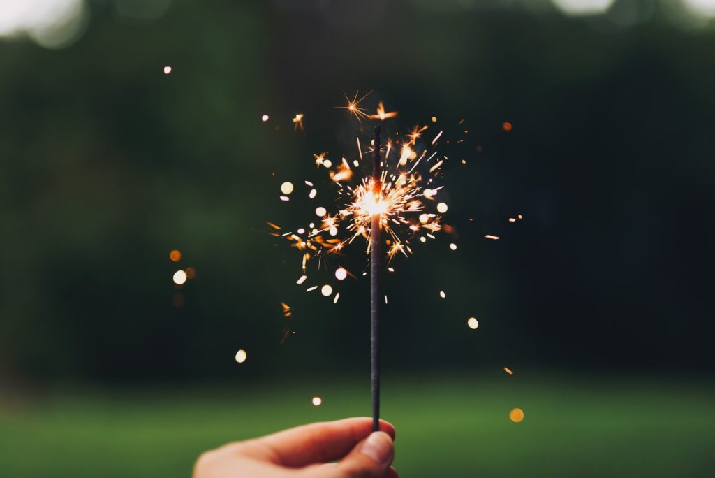 person holding sparkler with bokeh effect