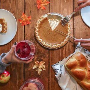 person slicing pie beside bread